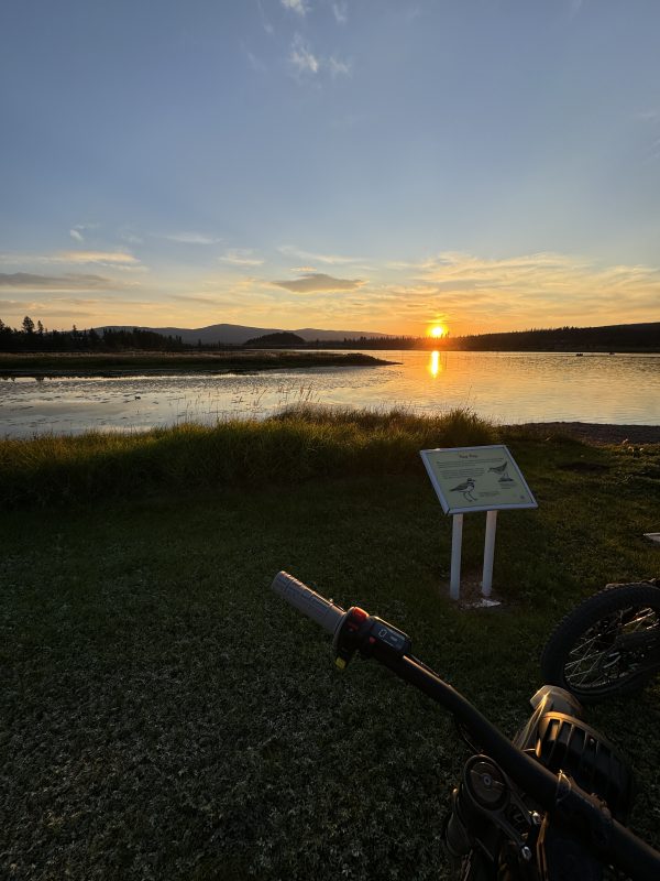 Handlebars of a bike beside an interpretive sign overlooking Leighton Lake as the sun sets
