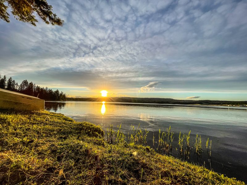 Sunset over Leighton Lake with golden light reflecting off calm water and a boat resting on the grassy shoreline